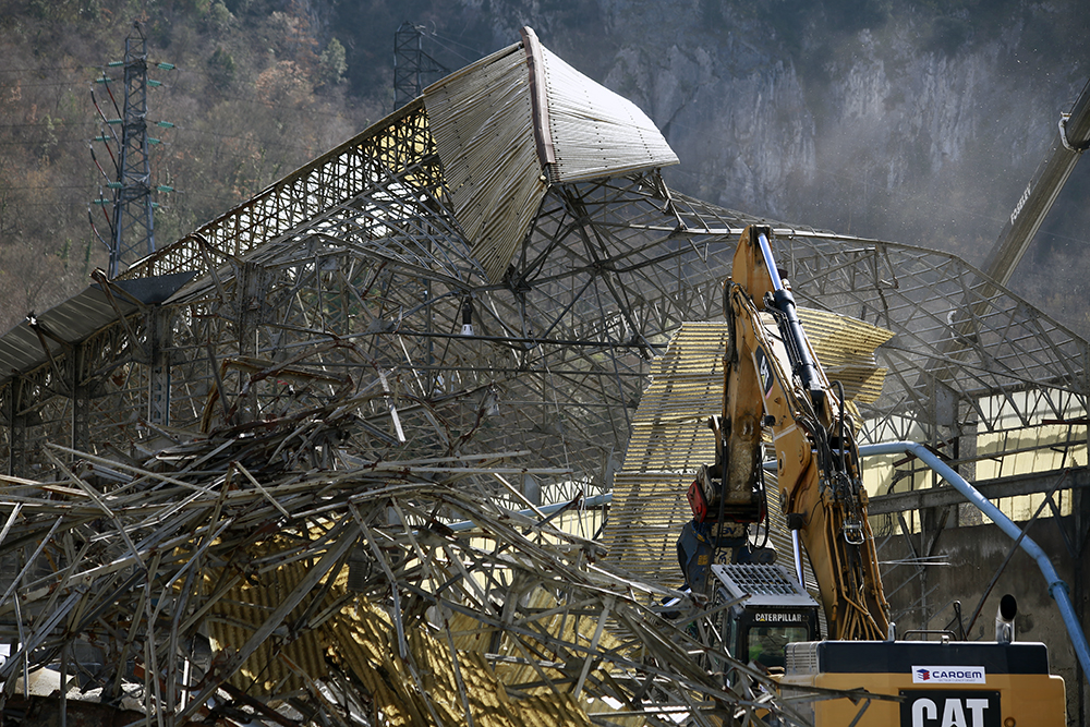 Chantier de démolition industrielle avec une pelle mécanique en train de démonter une grande structure métallique effondrée