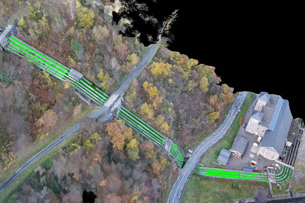Vue aérienne modélisée en 3D de canalisations industrielles traversant un paysage boisé et un bâtiment, avec tracé coloré pour l’analyse d’infrastructures