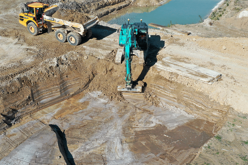Pelleteuse et camion intervenant sur un chantier de terrassement pour dépollution des sols en milieu naturel