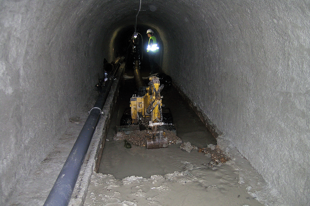 Curage de l'intérieur d'une conduite en béton par une équipe de Novacis avec une mini pelle 