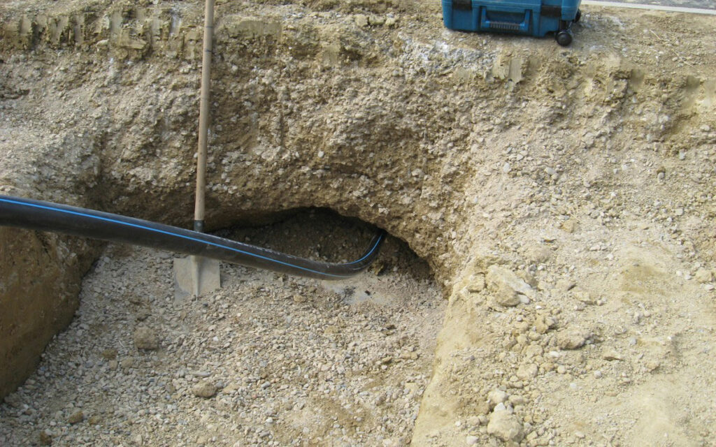 Cette image illustre un forage dirigé sous voierie, un câble passe sous la terre et la route